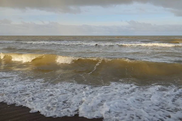 Kumlu bir sahilden (kum tepeleri) Baltık denizinin panoramik görüntüsü. Koyu bulutlu dramatik bir gökyüzü. Dalgalar, su sıçramaları. Idyllic deniz manzarası. Sıcak kış havası, iklim değişikliği, doğa. Danimarka