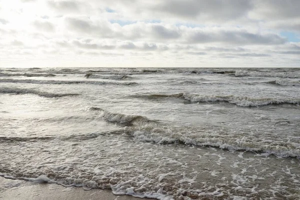 Fırtınadan sonra Baltık Denizi. Dramatik gökyüzü, parlayan bulutlar, yumuşak güneş ışığı. Dalgalar, su sıçratma. Resimli manzara, deniz manzarası, doğa. Panoramik görünüm