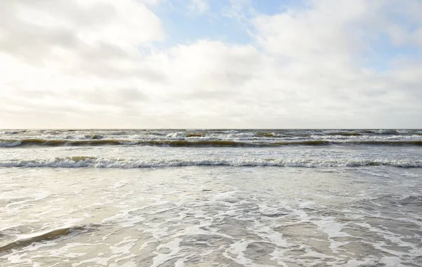 Kumlu sahilden Baltık denizinin panoramik görüntüsü (kum tepeleri). Parlak bulutlu dramatik bir gökyüzü. Dalgalar, su sıçramaları. Idyllic deniz manzarası. Bahar havası, iklim değişikliği, doğa