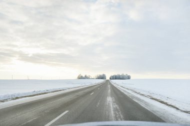 Karla kaplı orman ve kırsal alanda boş otoyol (asfalt yol). Kar sürükleniyor. Avrupa. Doğa, Noel tatilleri, uzak yerler, kış lastikleri, tehlikeli sürüş konsepti
