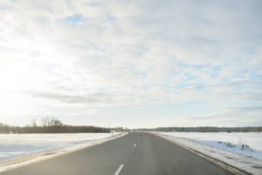 Karla kaplı orman ve kırsal alanda boş otoyol (asfalt yol). Kar sürükleniyor. Avrupa. Doğa, Noel tatilleri, uzak yerler, kış lastikleri, tehlikeli sürüş konsepti