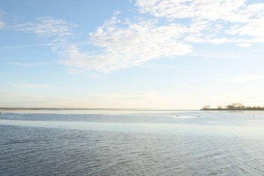 Gün batımında mavi orman gölü (nehir) panoramik hava manzarası. Yumuşak güneş ışığı, berrak gökyüzü, suya yansıyan yansımalar. Baharın başında. İdealist pastoral manzara. Doğa, çevre, ekoloji, eko-turizm