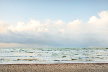 Fırtınadan sonra Baltık Denizi. Dramatik gökyüzü, parlayan bulutlar, yumuşak güneş ışığı. Dalgalar, su sıçratma. Resimli manzara, deniz manzarası, doğa. Panoramik görünüm