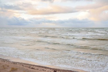 Fırtınadan sonra Baltık Denizi. Dramatik gökyüzü, parlayan bulutlar, yumuşak güneş ışığı. Dalgalar, su sıçratma. Resimli manzara, deniz manzarası, doğa. Panoramik görünüm