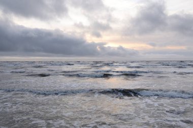 Fırtınadan sonra Baltık Denizi. Yumuşak günbatımı ışığı, çarpıcı parlayan bulutlar. Deniz manzarası, bulutlar, doğa. Panoramik manzara. Ekoloji, iklim değişikliği, hava durumu