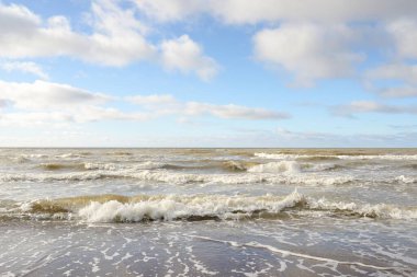 Fırtınadan sonra Baltık Denizi. Dramatik gökyüzü, parlayan bulutlar, yumuşak güneş ışığı. Dalgalar, su sıçratma. Resimli manzara, deniz manzarası, doğa. Panoramik görünüm