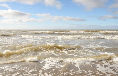 Fırtınadan sonra Baltık Denizi. Dramatik gökyüzü, parlayan bulutlar, yumuşak güneş ışığı. Dalgalar, su sıçratma. Resimli manzara, deniz manzarası, doğa. Panoramik görünüm