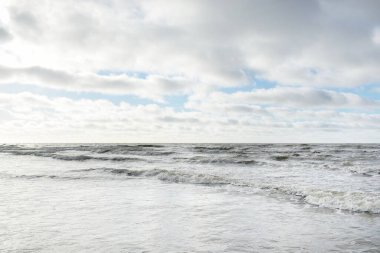 Fırtınadan sonra Baltık Denizi. Dramatik gökyüzü, parlayan bulutlar, yumuşak güneş ışığı. Dalgalar, su sıçratma. Resimli manzara, deniz manzarası, doğa. Panoramik görünüm