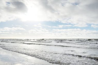 Fırtınadan sonra Baltık Denizi. Dramatik gökyüzü, parlayan bulutlar, yumuşak güneş ışığı. Dalgalar, su sıçratma. Resimli manzara, deniz manzarası, doğa. Panoramik görünüm