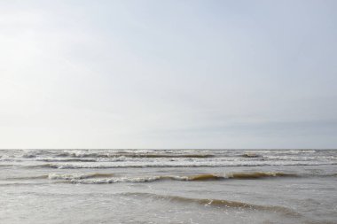 Gün batımında Baltık kıyısı. Yumuşak güneş ışığı, parlayan bulutlar, dalgalar ve su fışkıran berrak gökyüzü. Idyllic deniz manzarası. Hava, iklim değişikliği, doğa