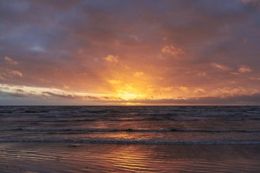 Fırtınadan sonra gün batımında Baltık Denizi. Dramatik gökyüzü, parlayan bulutlar, dofty altın güneş ışığı, dalgalar, fışkıran su. Resimli panoramik manzara. Doğa, çevre, ekoloji