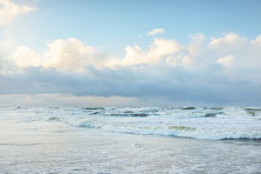 Fırtınadan sonra Baltık Denizi. Dramatik gökyüzü, parlayan bulutlar, yumuşak güneş ışığı. Dalgalar, su sıçratma. Resimli manzara, deniz manzarası, doğa. Panoramik görünüm