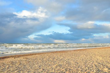 Gün batımında Baltık kıyısı. Kumsal, kum tepeleri. Dramatik gökyüzü akan bulutlar. Yumuşak güneş ışığı. Doğa, hava, çevre, eko turizm