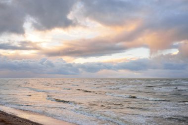 Fırtınadan sonra Baltık Denizi. Dramatik gökyüzü, parlayan bulutlar, yumuşak güneş ışığı. Dalgalar, su sıçratma. Resimli manzara, deniz manzarası, doğa. Panoramik görünüm