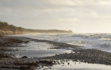 Gün batımında Baltık kıyılarından panoramik manzara. Dramatik bulutlar, parlayan bulutlar, fırtınadan sonra altın güneş ışığı. Doğa, çevre, iklim değişikliği, kararsız hava