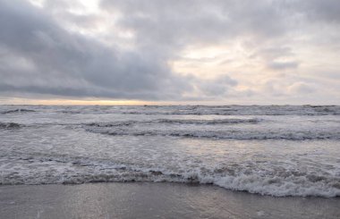 Fırtınadan sonra Baltık Denizi. Yumuşak günbatımı ışığı, çarpıcı parlayan bulutlar. Deniz manzarası, bulutlar, doğa. Sudaki yansımalar. Panoramik manzara. Ekoloji, iklim değişikliği, hava durumu