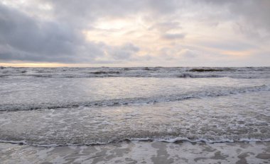 Fırtınadan sonra Baltık Denizi. Yumuşak günbatımı ışığı, çarpıcı parlayan bulutlar. Deniz manzarası, bulutlar, doğa. Sudaki yansımalar. Panoramik manzara. Ekoloji, iklim değişikliği, hava durumu