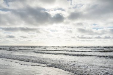 Fırtınadan sonra Baltık Denizi. Dramatik gökyüzü, parlayan bulutlar, yumuşak güneş ışığı. Dalgalar, su sıçratma. Resimli manzara, deniz manzarası, doğa. Panoramik görünüm