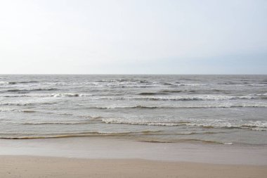 Gün batımında Baltık kıyısı. Yumuşak güneş ışığı, parlayan bulutlar, dalgalar ve su fışkıran berrak gökyüzü. Idyllic deniz manzarası. Hava, iklim değişikliği, doğa