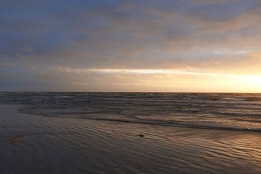 Fırtınadan sonra gün batımında Baltık Denizi. Dramatik gökyüzü, parlayan bulutlar, dofty altın güneş ışığı, dalgalar, fışkıran su. Resimli panoramik manzara. Doğa, çevre, ekoloji