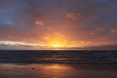 Fırtınadan sonra gün batımında Baltık Denizi. Dramatik gökyüzü, parlayan bulutlar, dofty altın güneş ışığı, dalgalar, fışkıran su. Resimli panoramik manzara. Doğa, çevre, ekoloji
