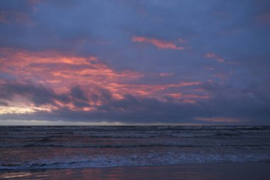 Fırtınadan sonra gün batımında Baltık Denizi. Dramatik gökyüzü, parlayan bulutlar, dofty altın güneş ışığı, dalgalar, fışkıran su. Resimli panoramik manzara. Doğa, çevre, ekoloji