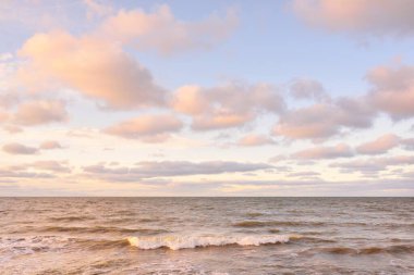 Gün batımında Baltık kıyıları (kum tepeleri). Yumuşak güneş ışığı, parlayan bulutlar, dalgalar ve su fışkıran berrak gökyüzü. Idyllic deniz manzarası. Liepaja, Letonya, Avrupa. Sıcak kış havası, iklim değişikliği, doğa