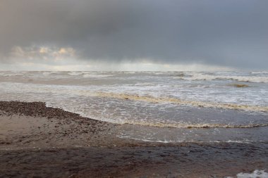 Gün batımında Baltık kıyısı. Kumsal, kum tepeleri. Dramatik gökyüzü akan bulutlar. Yumuşak güneş ışığı. Doğa, hava, çevre, eko turizm