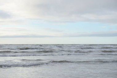 Fırtınadan sonra Baltık Denizi. Yumuşak günbatımı ışığı, çarpıcı parlayan bulutlar. Deniz manzarası, bulutlar, doğa. Panoramik manzara. Ekoloji, iklim değişikliği, hava durumu