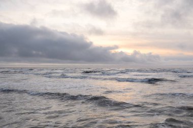 Fırtınadan sonra Baltık Denizi. Yumuşak günbatımı ışığı, çarpıcı parlayan bulutlar. Deniz manzarası, bulutlar, doğa. Panoramik manzara. Ekoloji, iklim değişikliği, hava durumu