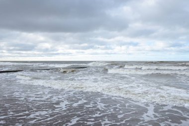 Fırtınadan sonra Baltık Denizi. Dramatik gökyüzü, parlayan bulutlar, yumuşak güneş ışığı. Dalgalar, su sıçratma. Resimli manzara, deniz manzarası, doğa. Panoramik görünüm
