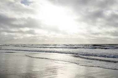 Kumlu sahilden Baltık denizinin panoramik görüntüsü (kum tepeleri). Parlak bulutlu dramatik bir gökyüzü. Dalgalar, su sıçramaları. Idyllic deniz manzarası. Bahar havası, iklim değişikliği, doğa