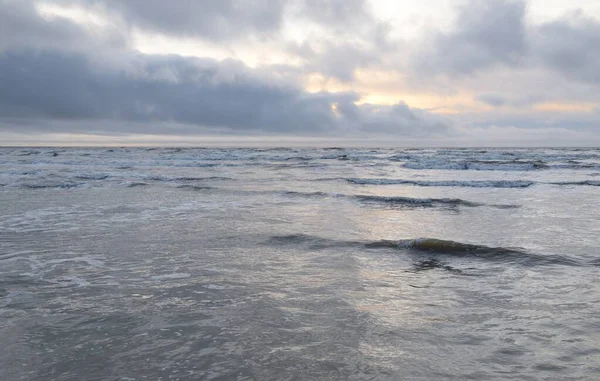 Fırtınadan sonra Baltık Denizi. Yumuşak günbatımı ışığı, çarpıcı parlayan bulutlar. Deniz manzarası, bulutlar, doğa. Panoramik manzara. Ekoloji, iklim değişikliği, hava durumu