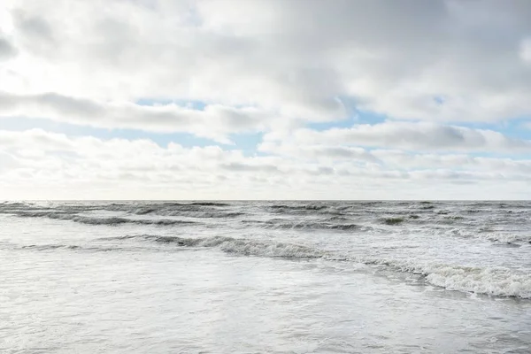 Fırtınadan sonra Baltık Denizi. Dramatik gökyüzü, parlayan bulutlar, yumuşak güneş ışığı. Dalgalar, su sıçratma. Resimli manzara, deniz manzarası, doğa. Panoramik görünüm