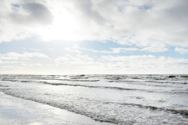 Fırtınadan sonra Baltık Denizi. Dramatik gökyüzü, parlayan bulutlar, yumuşak güneş ışığı. Dalgalar, su sıçratma. Resimli manzara, deniz manzarası, doğa. Panoramik görünüm