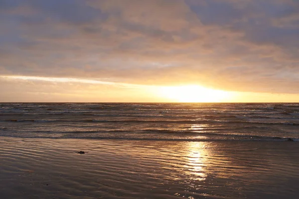 Fırtınadan sonra gün batımında Baltık Denizi. Dramatik gökyüzü, parlayan bulutlar, dofty altın güneş ışığı, dalgalar, fışkıran su. Resimli panoramik manzara. Doğa, çevre, ekoloji