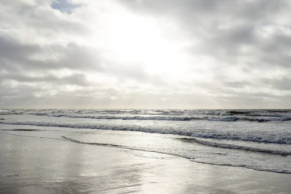 Kumlu sahilden Baltık denizinin panoramik görüntüsü (kum tepeleri). Parlak bulutlu dramatik bir gökyüzü. Dalgalar, su sıçramaları. Idyllic deniz manzarası. Bahar havası, iklim değişikliği, doğa