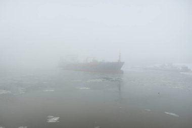 Donmuş nehir, büyük bir kargo gemisi. Kar, kalın sis. Kış kentsel manzarası kavramı. Ulaşım, denizcilik gemisi, küresel iletişim, endüstri, lojistik