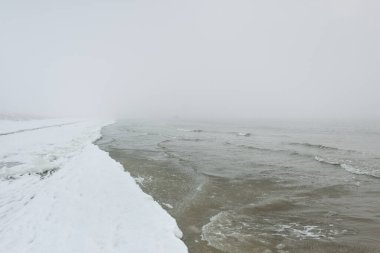 Sis içindeki Baltık Denizi. Dalgalar, su sıçratma, fırtına. Doğal dokular. Resimli panoramik monokrom manzarası, deniz manzarası. Doğa, çevre, sert hava, tehlike