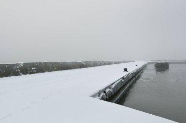 Kumlu sahilden Baltık Denizi 'nin panoramik manzarası. Deniz fenerine dolaş, dalgalar. Yoğun beyaz sis, sis, kar. Dalgalar, su sıçramaları. Deniz Burnu. Tek renkli kış manzarası