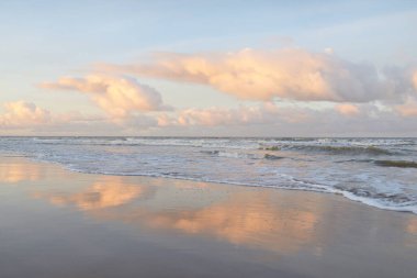 Fırtınadan sonra gün batımında Baltık Denizi. Dramatik gökyüzü, parlayan bulutlar, dofty altın güneş ışığı, dalgalar, fışkıran su. Resimli panoramik manzara. Doğa, çevre, ekoloji