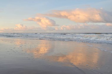 Fırtınadan sonra gün batımında Baltık Denizi. Dramatik gökyüzü, parlayan bulutlar, dofty altın güneş ışığı, dalgalar, fışkıran su. Resimli panoramik manzara. Doğa, çevre, ekoloji