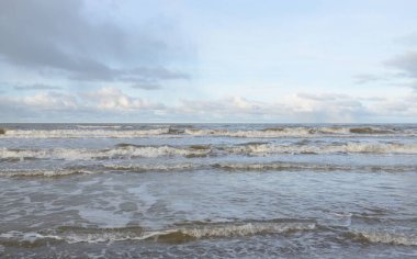 Kumlu bir sahilden (kum tepeleri) Baltık denizinin panoramik görüntüsü. Koyu bulutlu dramatik bir gökyüzü. Dalgalar, su sıçramaları. Idyllic deniz manzarası. Sıcak kış havası, iklim değişikliği, doğa. Danimarka