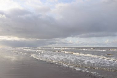 Kumlu bir sahilden (kum tepeleri) Baltık denizinin panoramik görüntüsü. Koyu bulutlu dramatik bir gökyüzü. Dalgalar, su sıçramaları. Idyllic deniz manzarası. Sıcak kış havası, iklim değişikliği, doğa. Danimarka