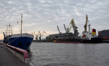 Kargo portu terminalinde demirli vakum zıpzıpzıpı ve büyük gemi. Vinçler arka planda. Letonya 'da sızıntı var. Nakliye, endüstri, lojistik