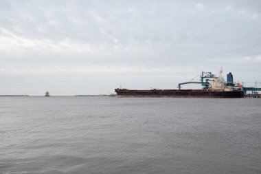 Kargo iskelesine demir atmış büyük bir gemi. Vinçler arka planda. Letonya 'da sızıntı var. Nakliye, endüstri, lojistik