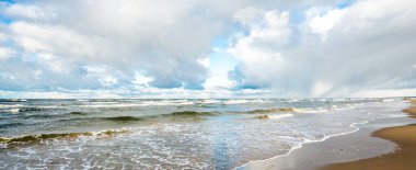 Kumlu bir sahilden (kum tepeleri) Baltık denizinin panoramik görüntüsü. Koyu bulutlu dramatik bir gökyüzü. Dalgalar, su sıçramaları. Idyllic deniz manzarası. Sıcak kış havası, iklim değişikliği, doğa