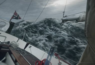 Fırtınada denizde yüzen topuklu bir yat, kokpitten bir manzara. Karanlık dalgalar, su sıçramaları. Uzun pozlama, hareket. Kötü hava, kasırga, tehlike, destansı deniz manzarası. Yarış, yarış, spor