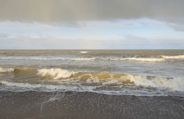 Kumlu bir sahilden (kum tepeleri) Baltık denizinin panoramik görüntüsü. Koyu bulutlu dramatik bir gökyüzü. Dalgalar, su sıçramaları. Idyllic deniz manzarası. Sıcak kış havası, iklim değişikliği, doğa. Danimarka