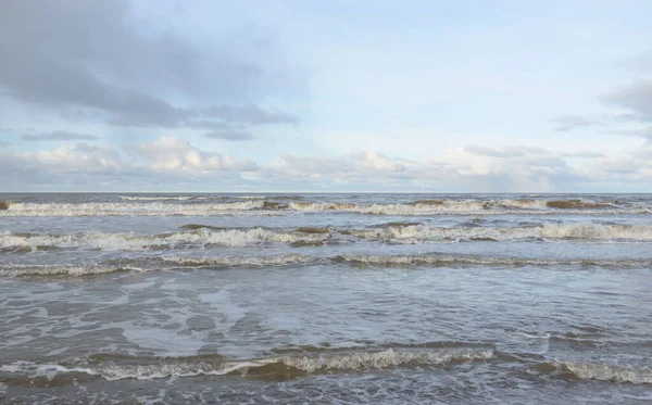 Kumlu bir sahilden (kum tepeleri) Baltık denizinin panoramik görüntüsü. Koyu bulutlu dramatik bir gökyüzü. Dalgalar, su sıçramaları. Idyllic deniz manzarası. Sıcak kış havası, iklim değişikliği, doğa. Danimarka